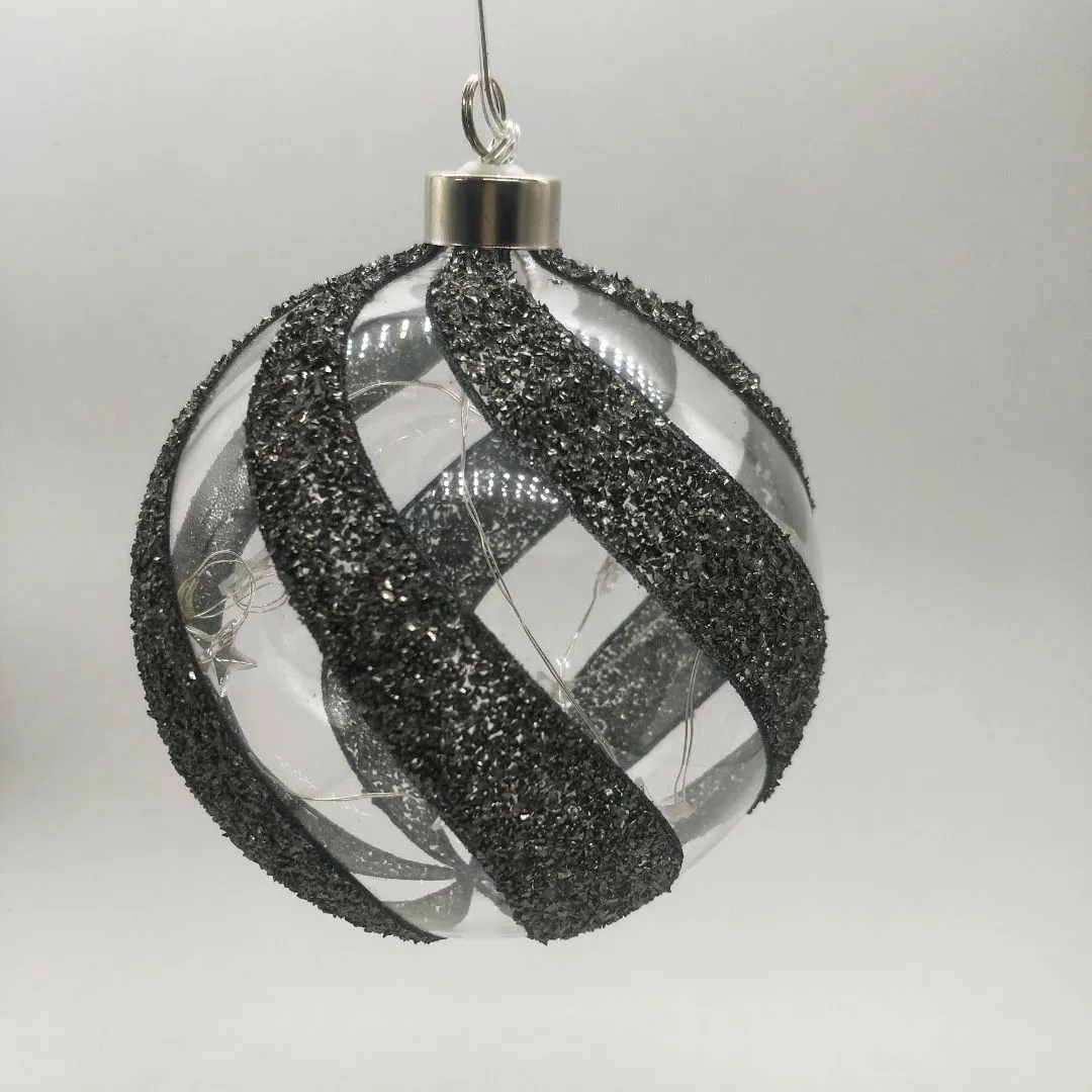 This product uses a process of gluing glitter onto the glass, and then adding a ribbon design. It is also battery operated and has an LED light inside.