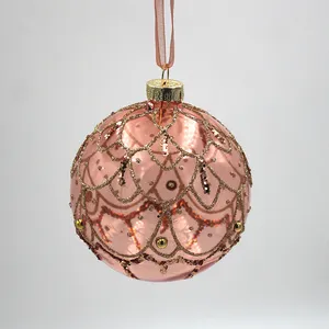 The rose gold glass Christmas ornament is hand-blown and decorated with intricate details.