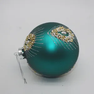 This teal blue Christmas ornament features a delicate hand-painted design with gold and white decorations.