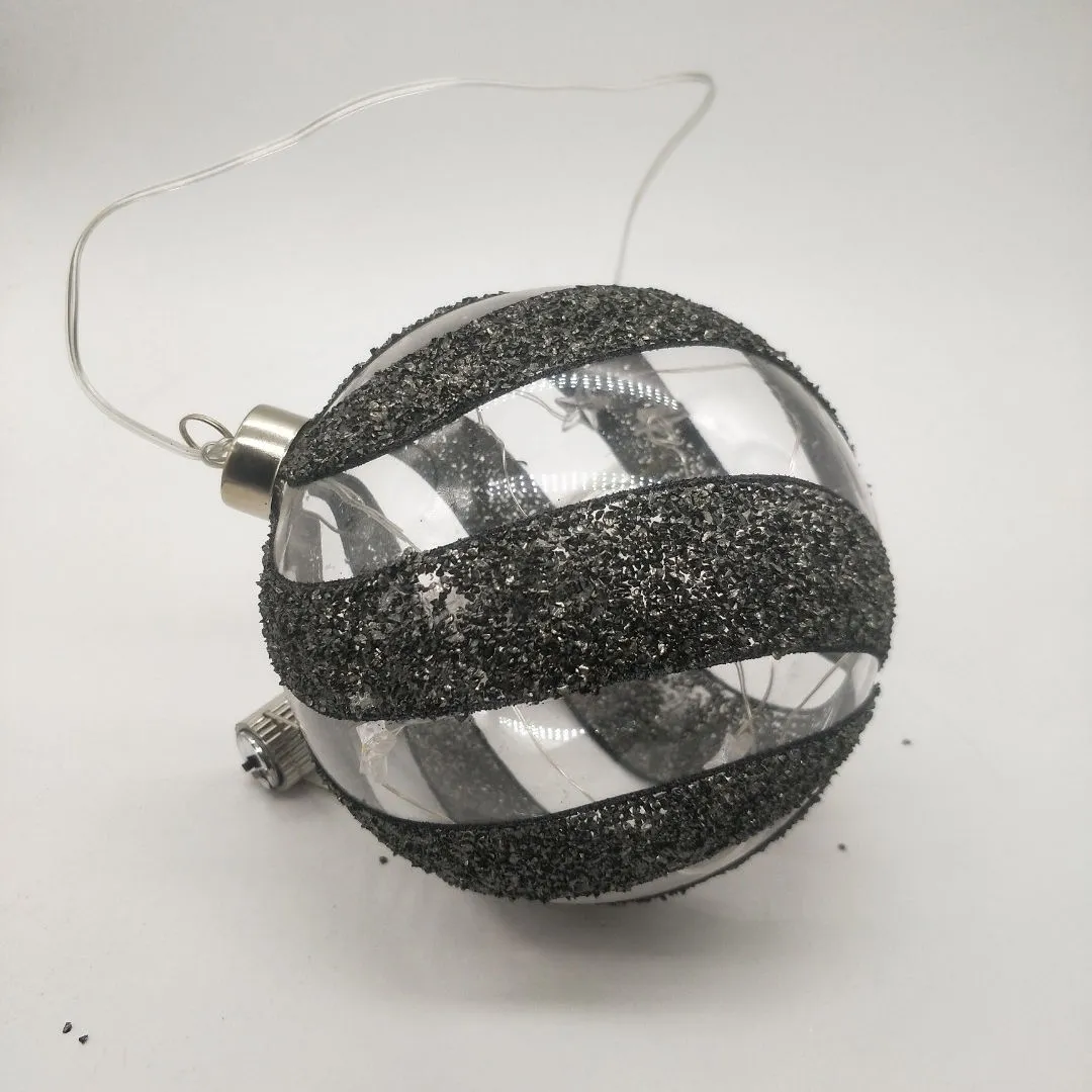 This product is made by blowing glass and then decorated with glitter and ribbon. It is also battery-operated and has an LED light inside.