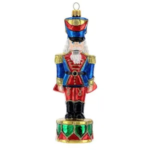 This glass ornament is a charming addition to your holiday decor. It features a traditional nutcracker design, standing tall and ready to guard your tree. This handmade ornament is perfect for adding a touch of whimsy to your celebrations.