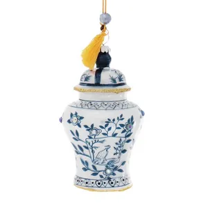 This glass ornament is a lovely ginger jar shape with a detailed floral design in blue and gold on a white background. It has a shiny blue tassel, adding to its charming appearance. The intricate detail makes it a unique and special addition to any holiday decor.