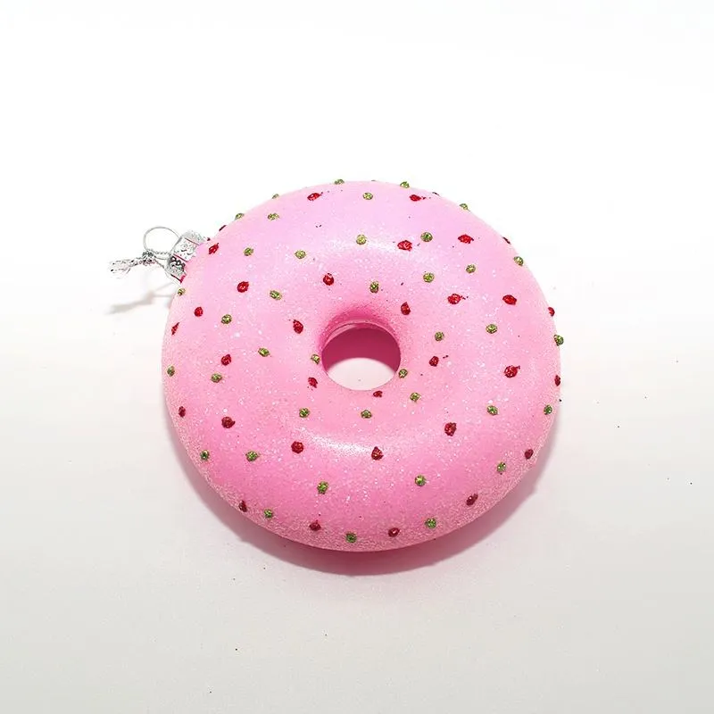 This product is a pink glazed donut shaped Christmas ornament with red and green sprinkles.