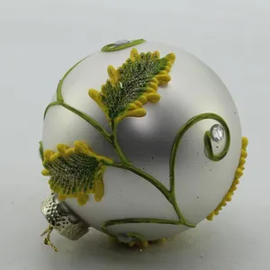 This product is a wholesale silver glass Christmas ornament ball decorated with yellow leaves and a glittery finish, perfect for adding a touch of elegance to your holiday decor.