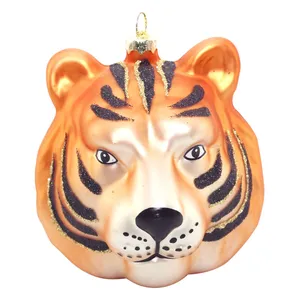 This product is a glass ornament featuring a tiger head design. It's meticulously crafted with black stripes and glitter, adding a touch of elegance to your holiday decor.